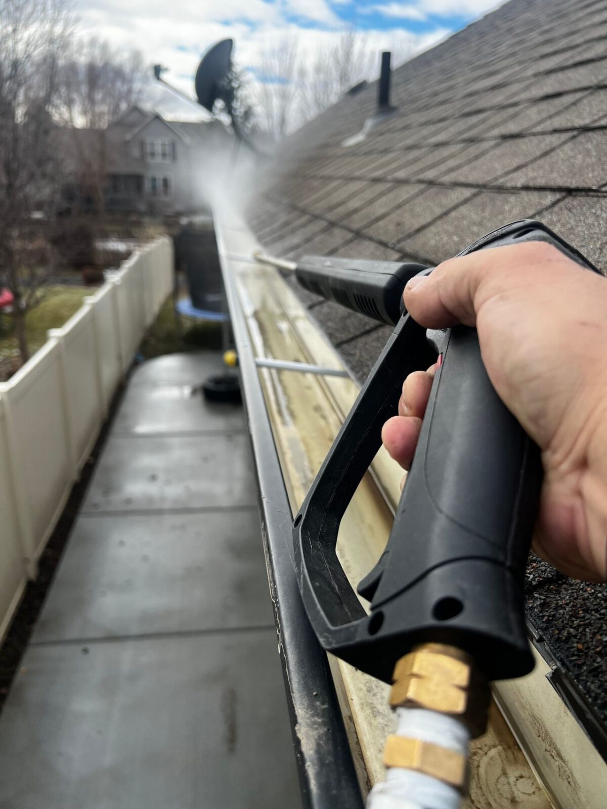 Worker cleaning leaves from a residential gutter in Houston